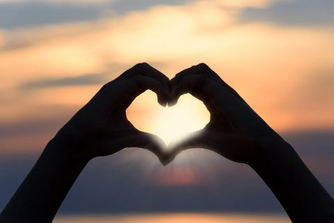 heart shape made by hands with sunlight coming through