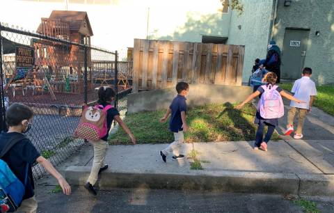 Children at Bayaan Academy practicing social distancing and wearing face masks in a line heading into school.