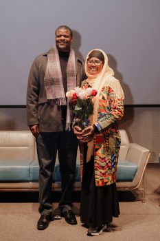 Dr. Patricia standing with son Wali on stage with flowers